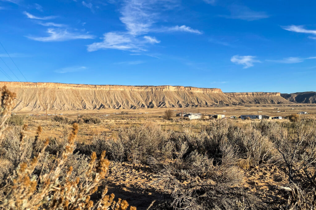 a landscape shot of a dry looking field with a raised flat hill in the background