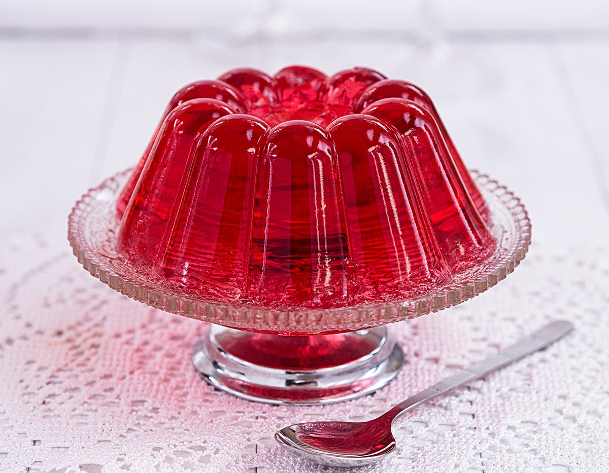 Red jello mold on a clear cake stand.