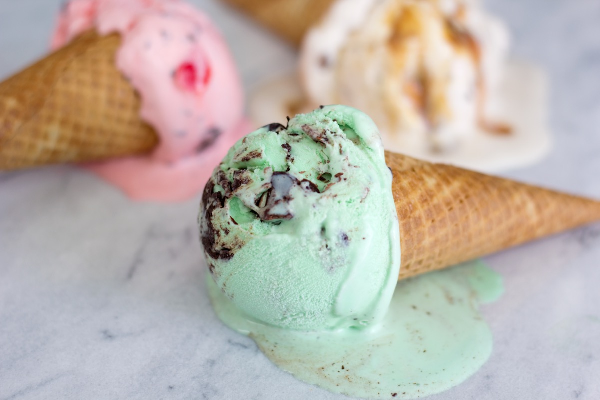 Close up of three ice cream cones melting on a marble countertop. 