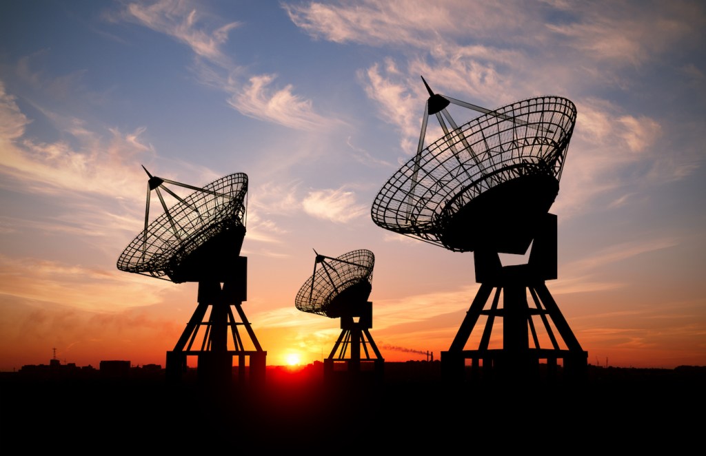 Three satellite dishes at sunset.