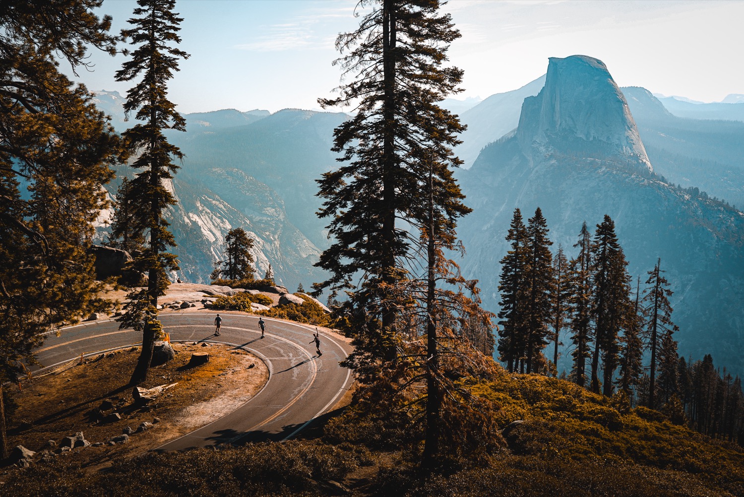 a landscape shot of yosemite national park with three people on a winding road