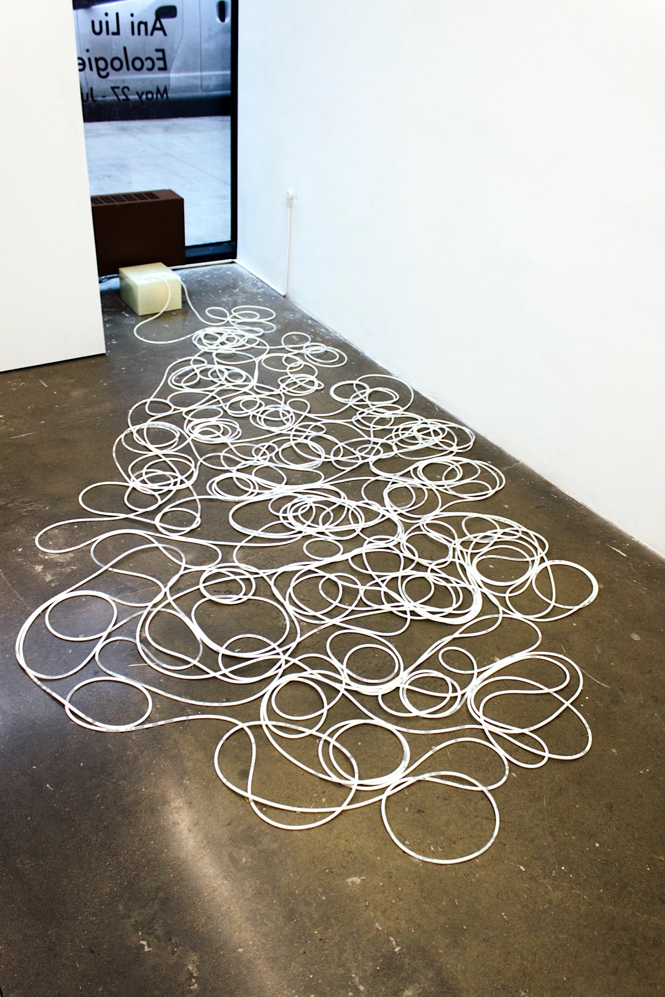 a huge coil and mess of thin tubing on a concrete floor filled with a white fluid
