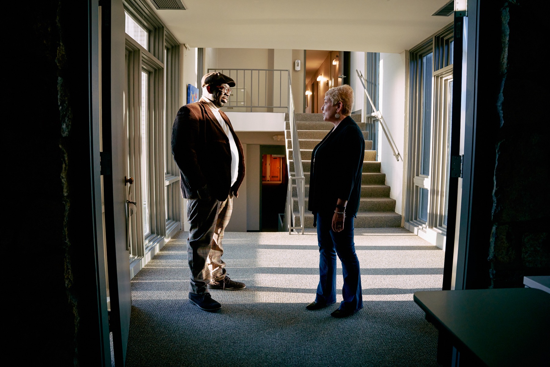 an older black man and an older white woman talking in a common space in a building