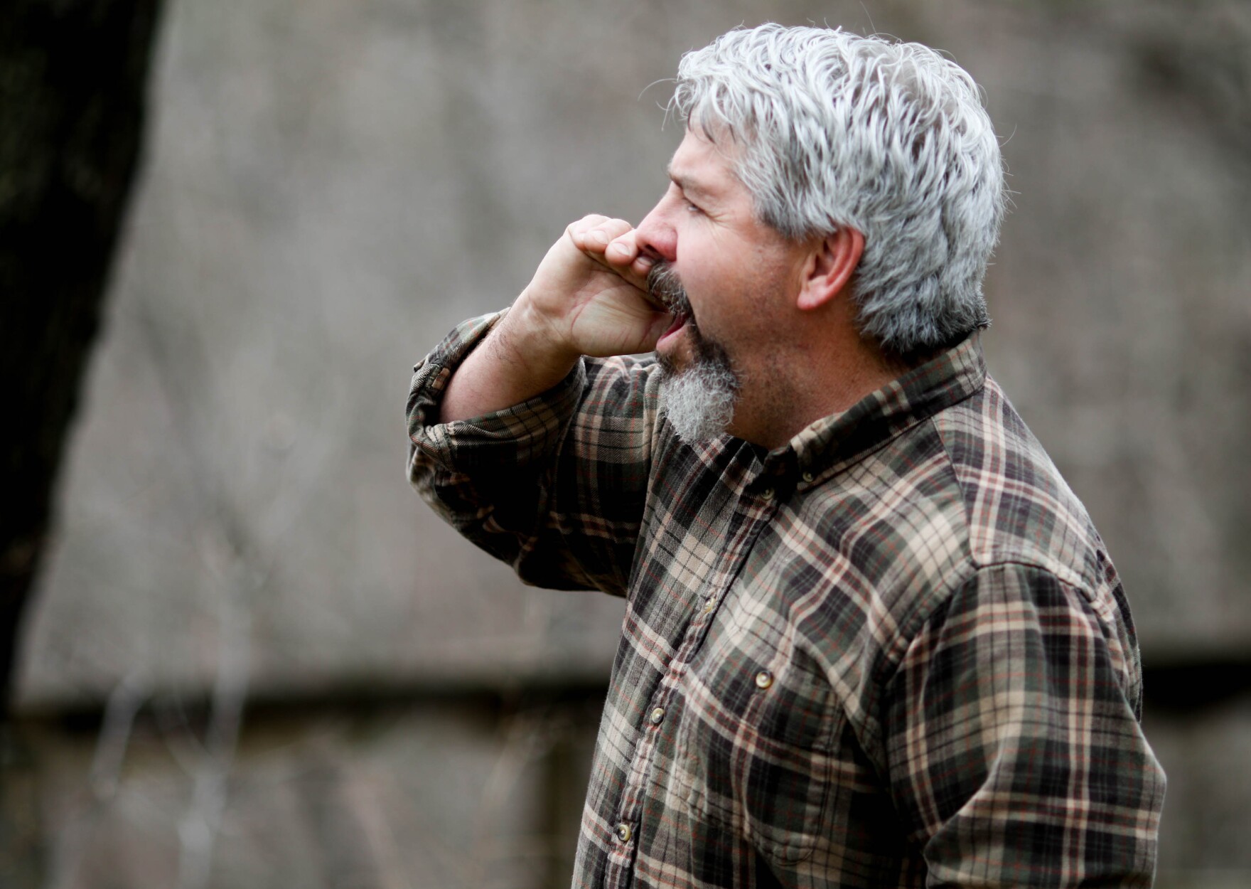 A man talking on the phone outdoors, looking away from the camera
