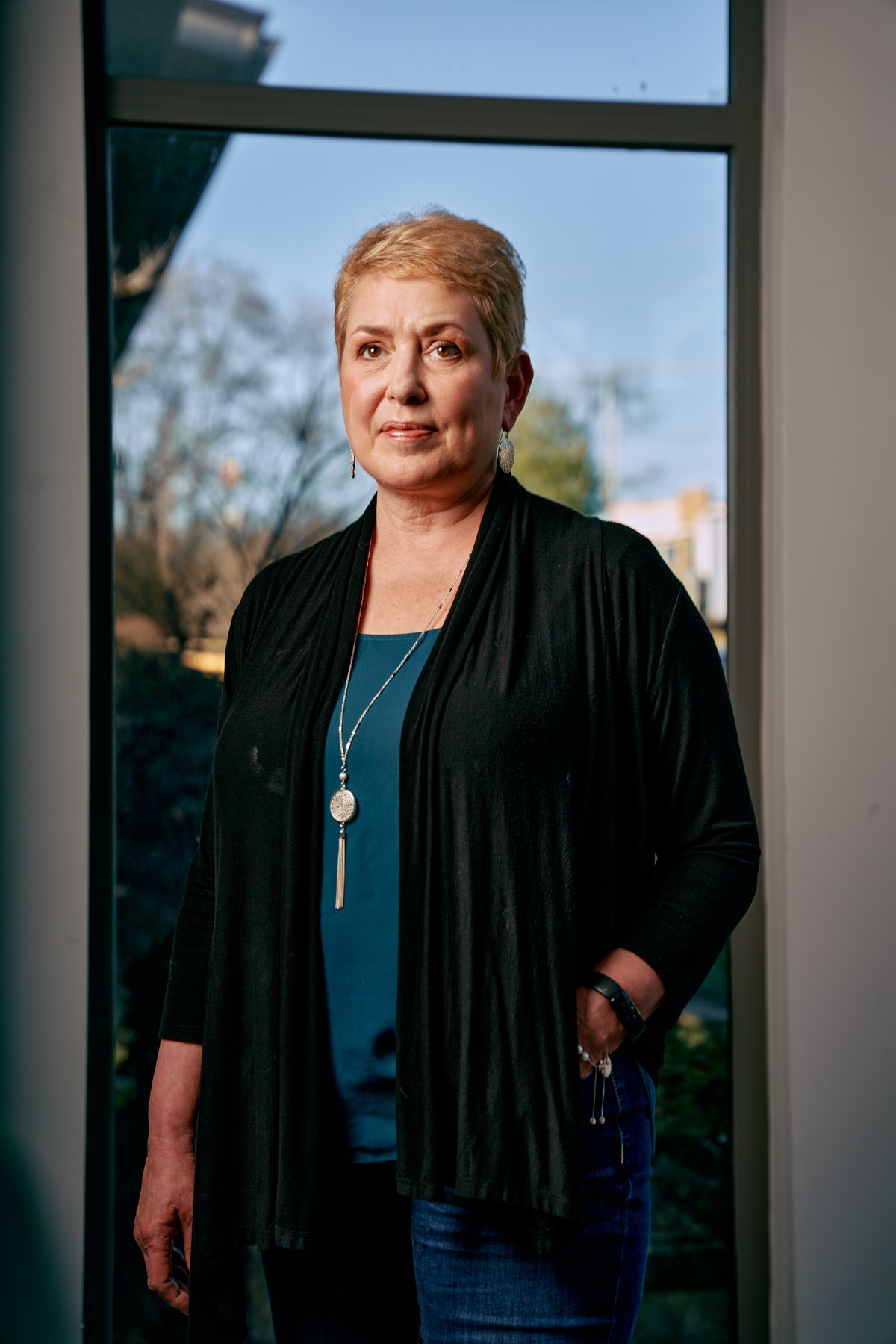 a woman with short blonde hair with a neutral expression looking off into the distance