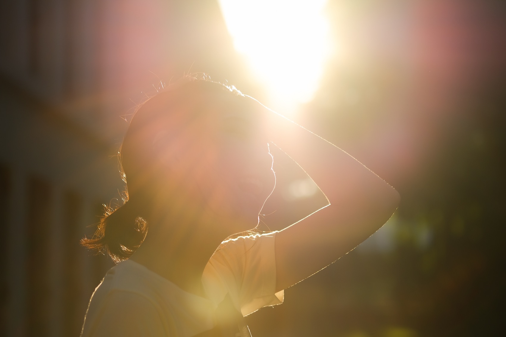 a woman looking up at the sun, which is so bright that it's silhouetting her