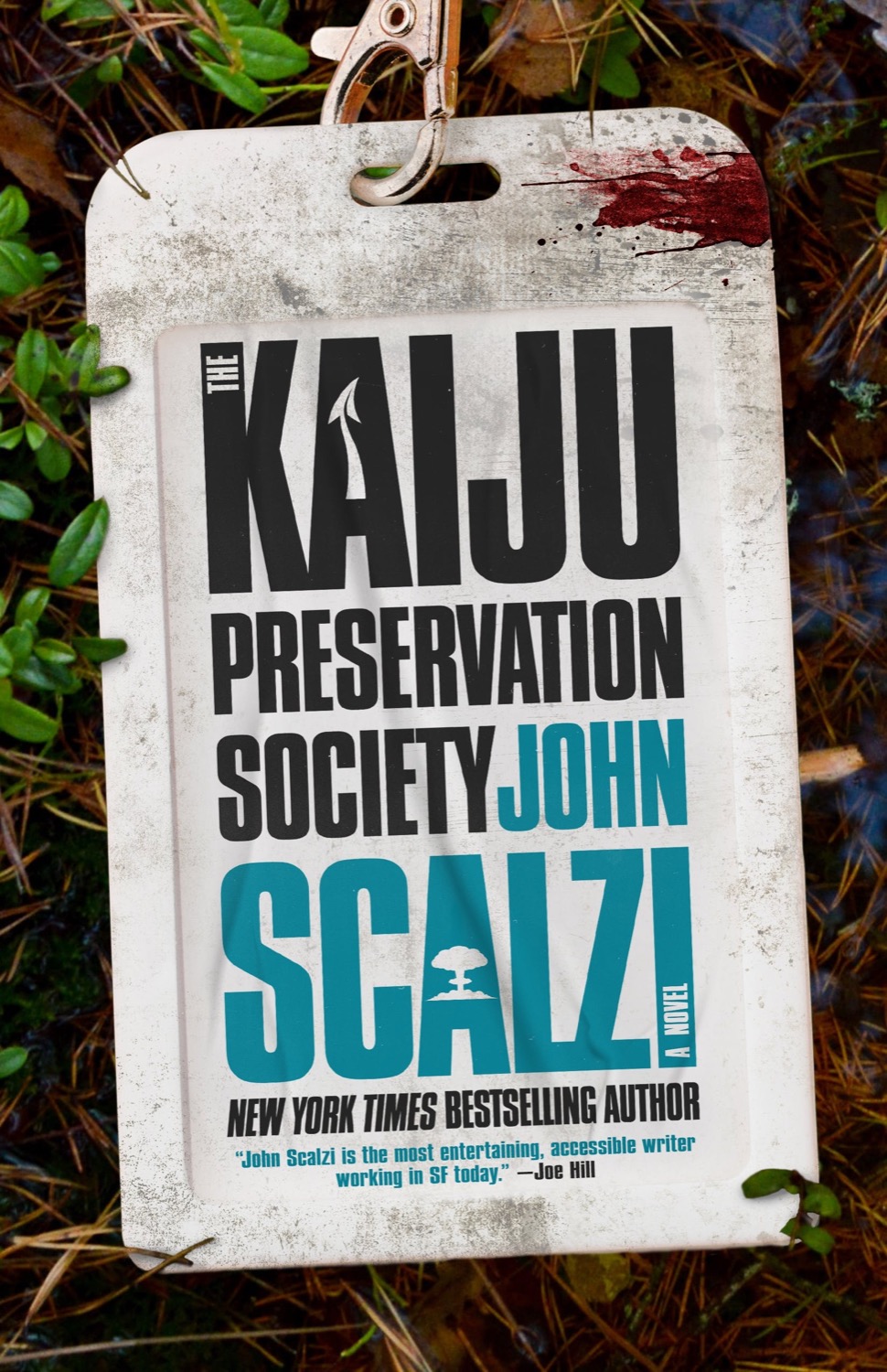 a book cover of a dirtied, bloddied name that attached to a landyard that says 'The Kaiju Preservation Society by new york times best-selling authorJohn Scalzi'