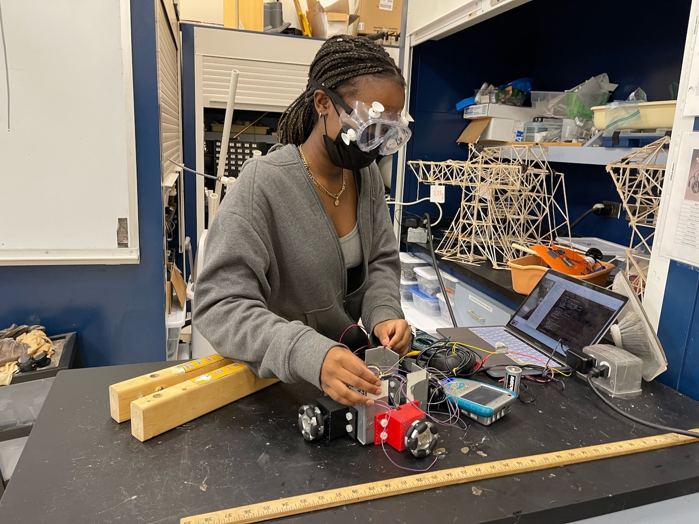 Elizabeth Nyamwange wearing safety goggles tinkering on an engineering work table. 