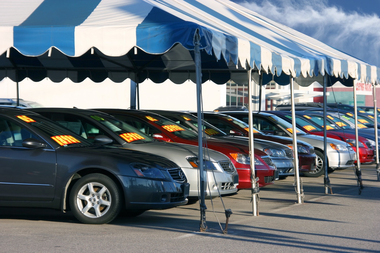 a lot with about a dozen used cars with large prices on their windshields