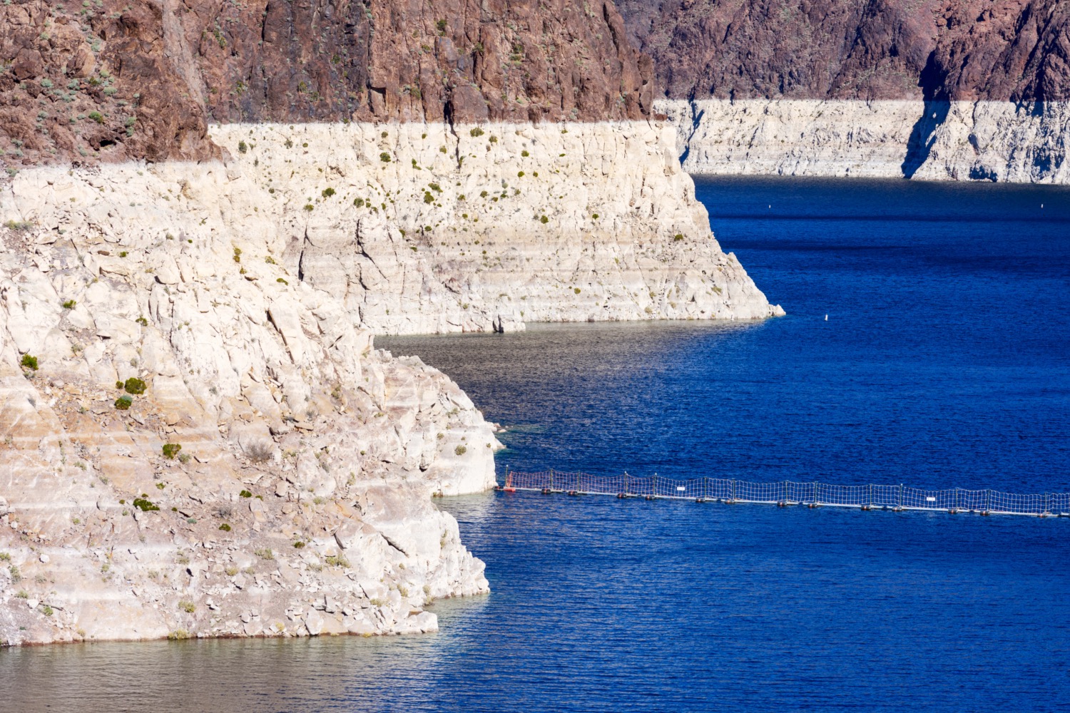 a lake with mountains surrounding it, with a consistent ring of whiter rock above the lake where the water line used to be