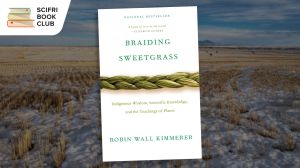 The cover of the book "Braiding Sweetgrass" by Robin Wall Kimmerer over a photo of a field with scant wheat and snow on the ground, with mountains in the far distance. The SciFri Book Club logo is in the upper left hand corner.