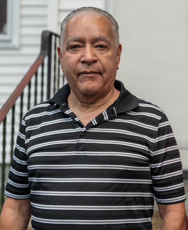 A man waearing a striped polo shirt looks at the camera for a photo.
