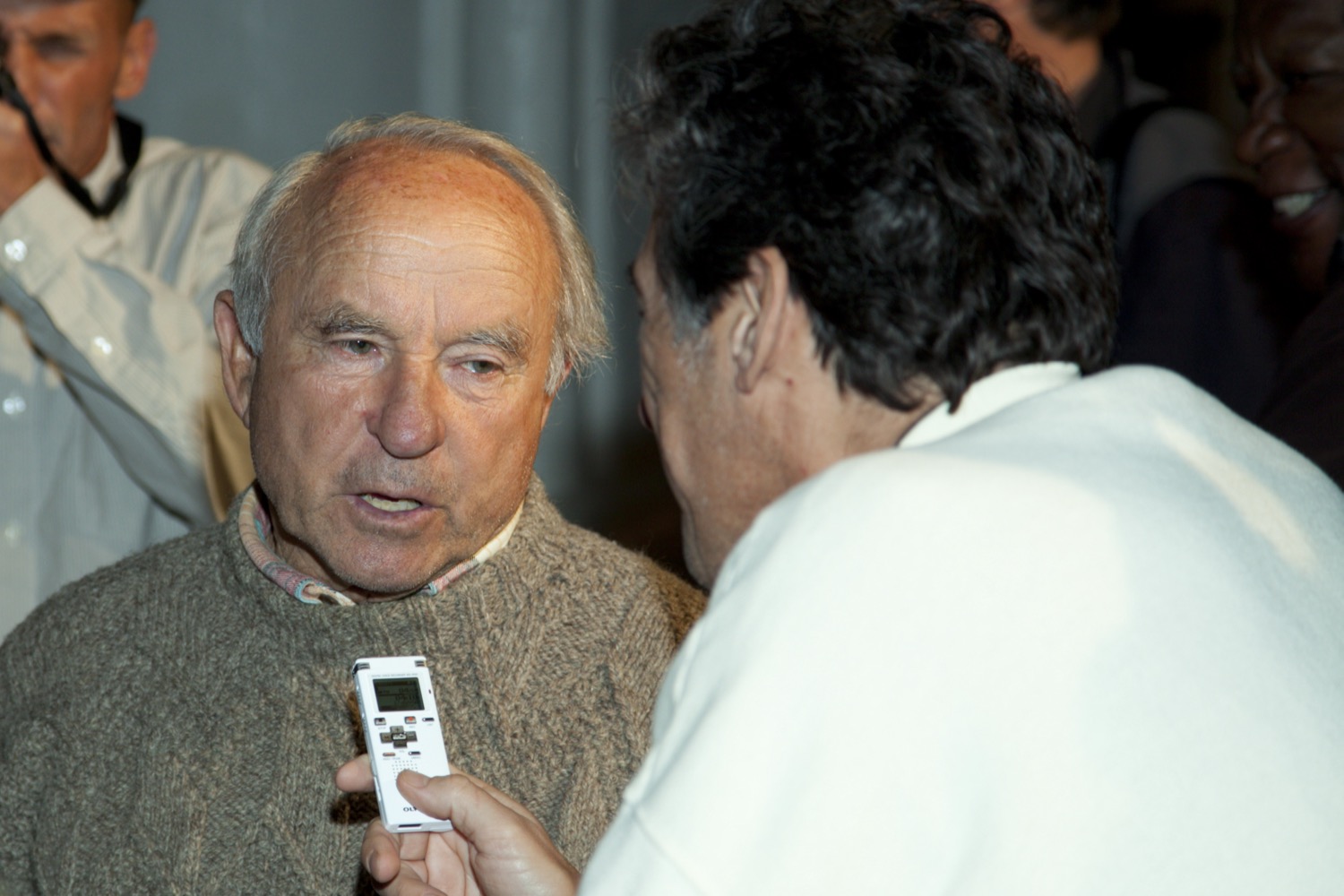 an older white man being tape recorded by another man who's back is to the camera