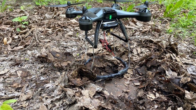 A small drone hovering over dirt, prodding into it.