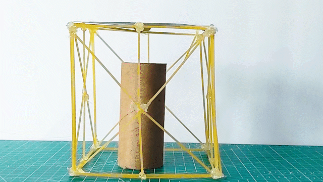 A structure made of spaghetti collapses under the weight of a stack of coins.