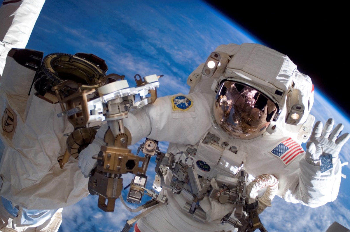 An astronaut in a full spacesuit fixes the ISS in space.