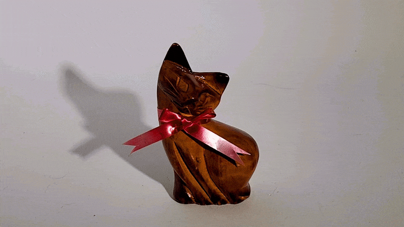 An animated GIF of a cat figurine casting a shadow behind it that moves with the light.