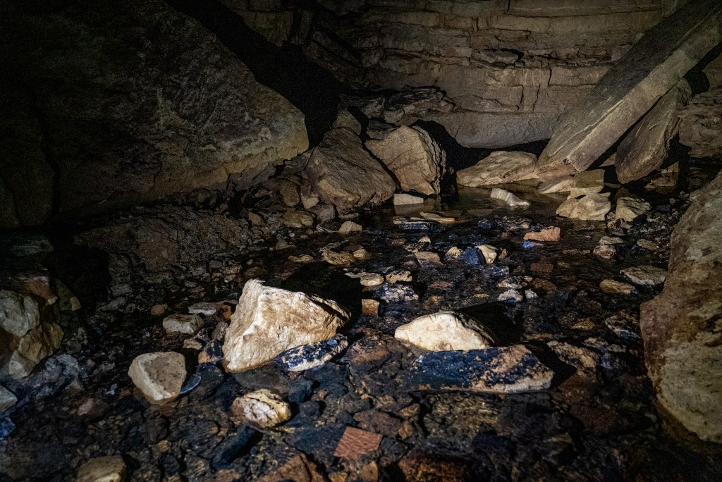 A shallow, watery pool at the bottom of a cave