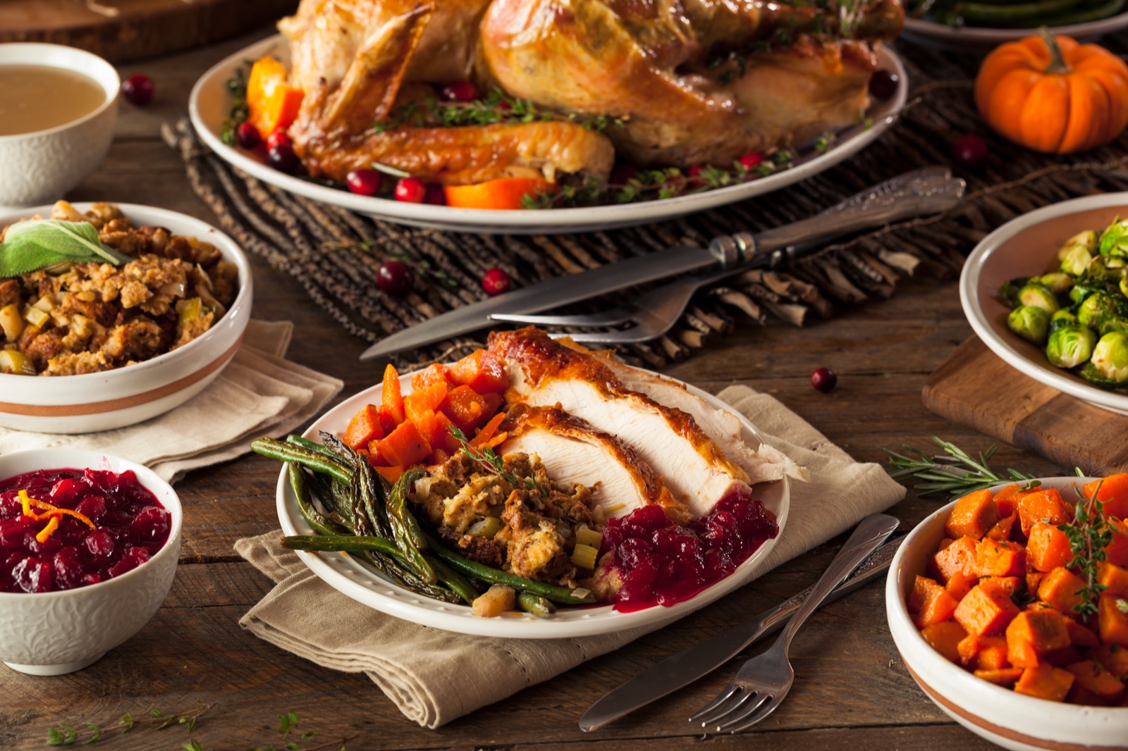 a thanksgiving meal spread of turkey, cranberries, asparagus, carrots and more