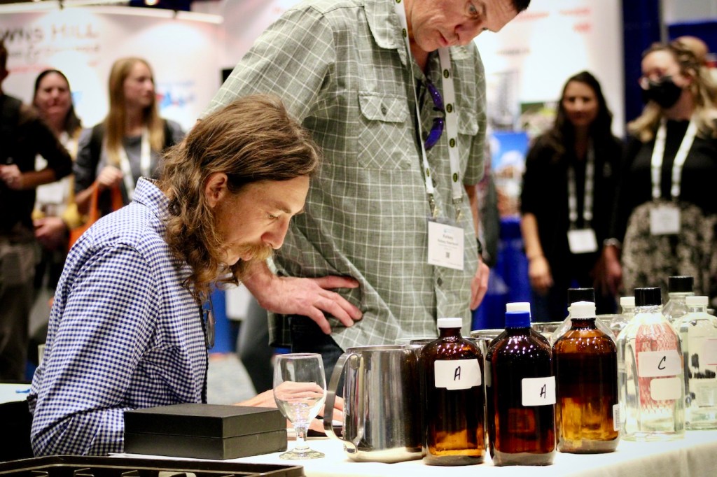 A man with bottles labeled with letters takes notes.