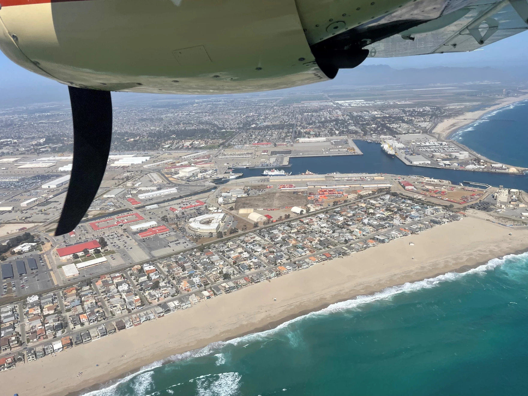 an ariel view looking out the window of a small propellor plane, looking out onto southern california coastline