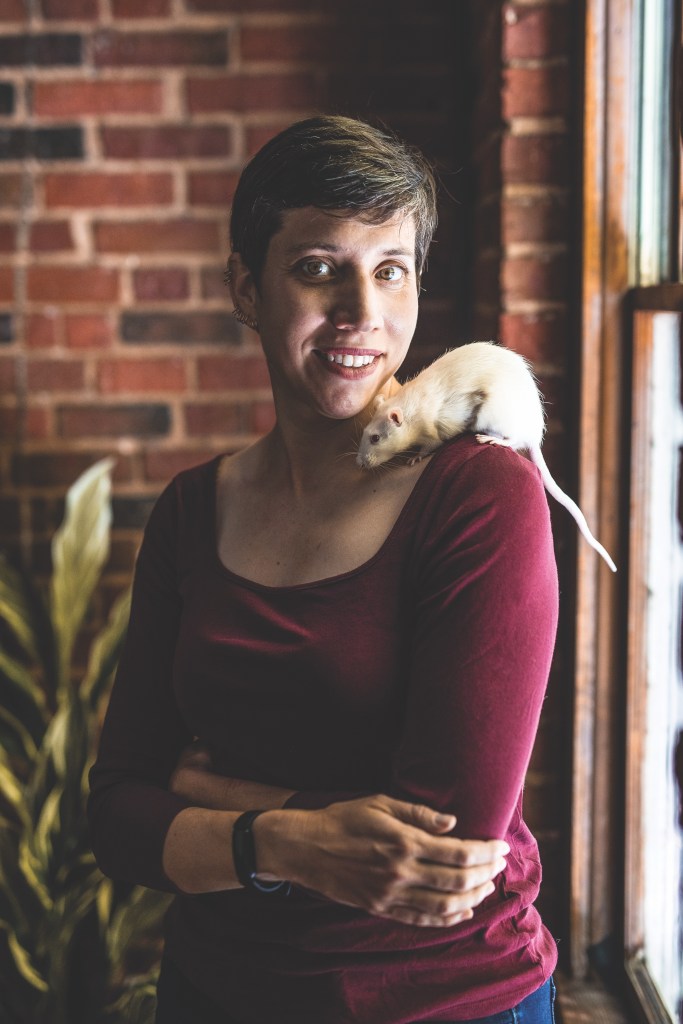 A woman with a rat on her shoulder.