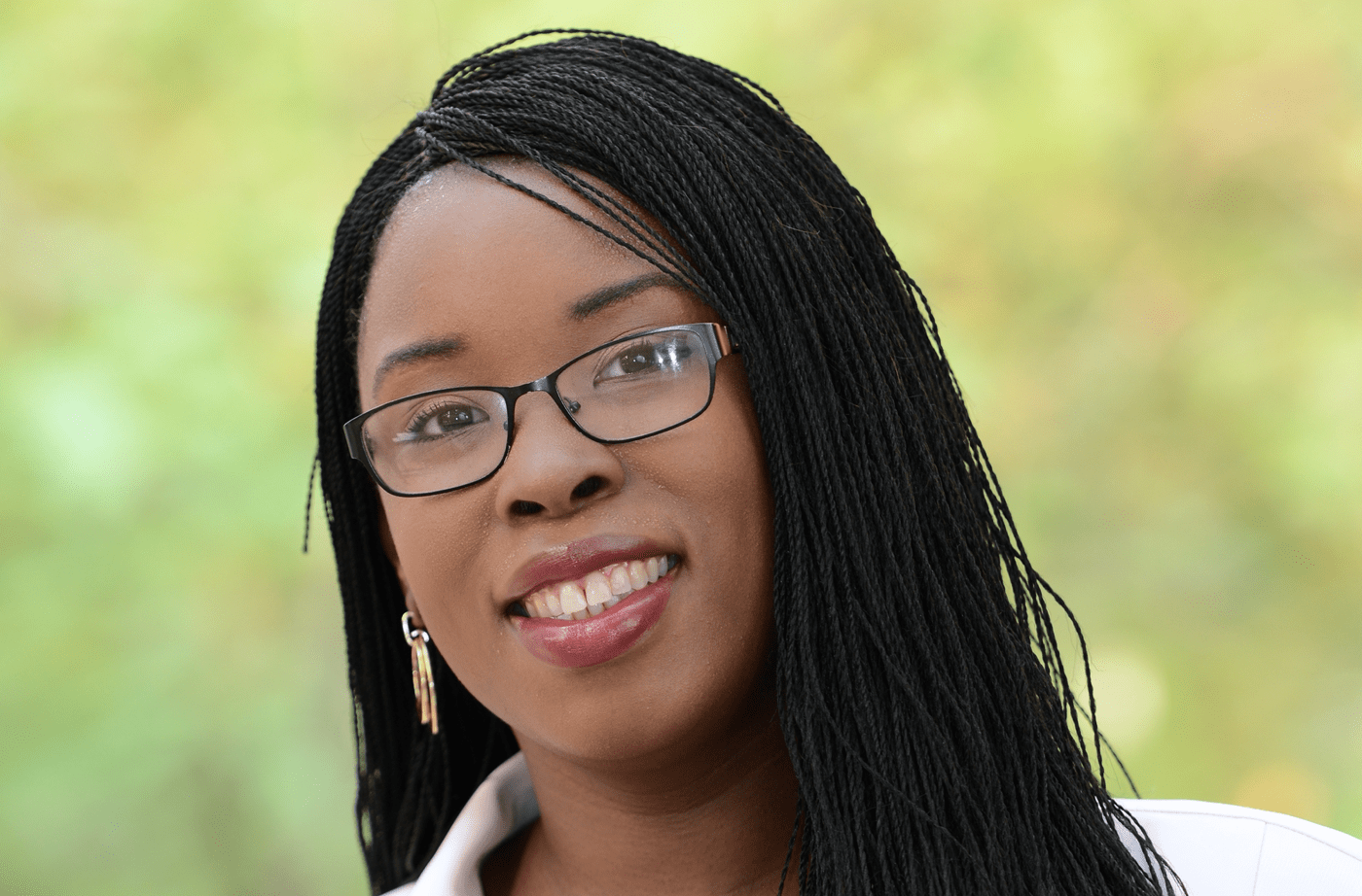 a headshot of a black woman wearing glasses smiling