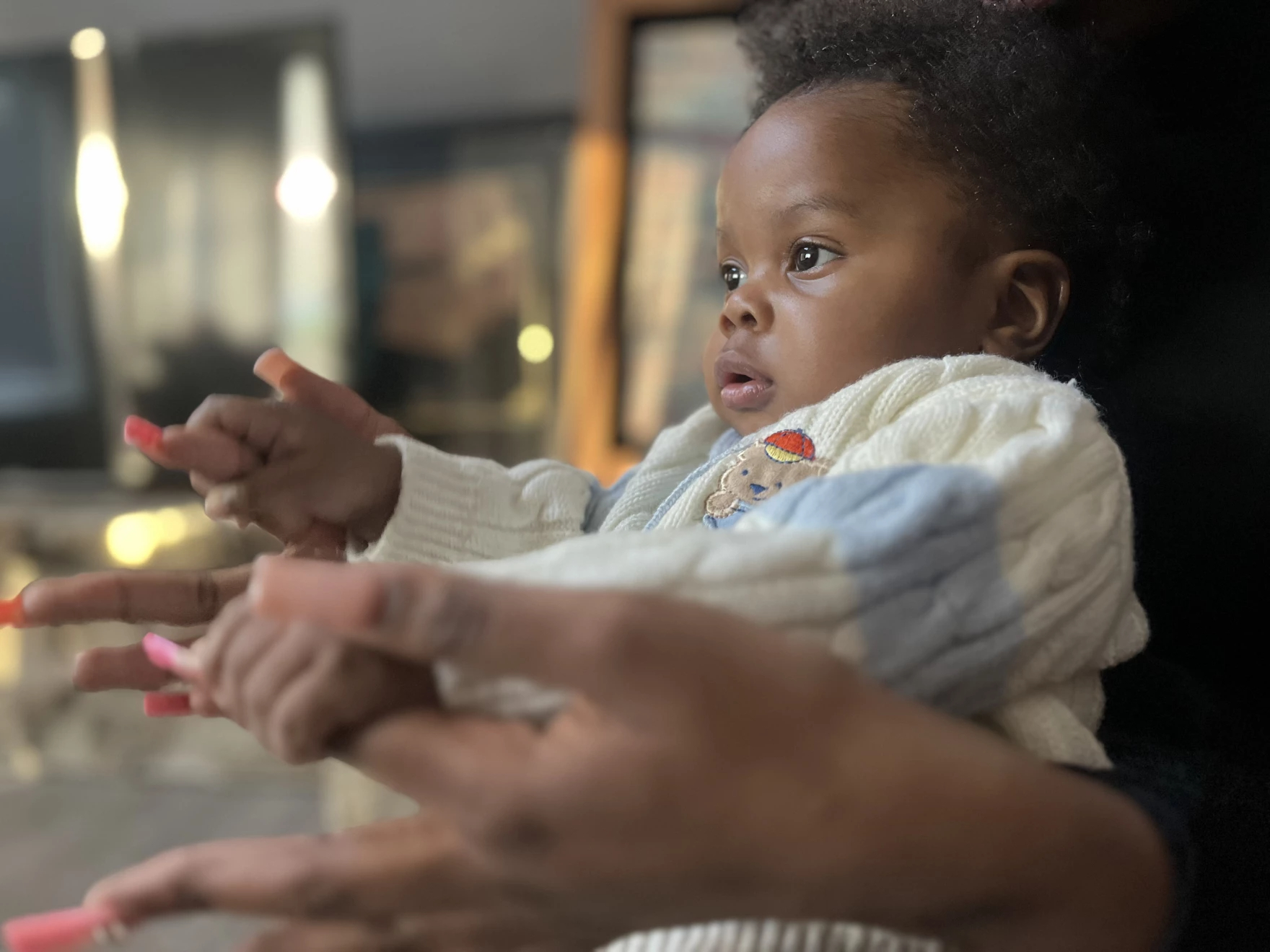 a baby in warm clothes reaches out