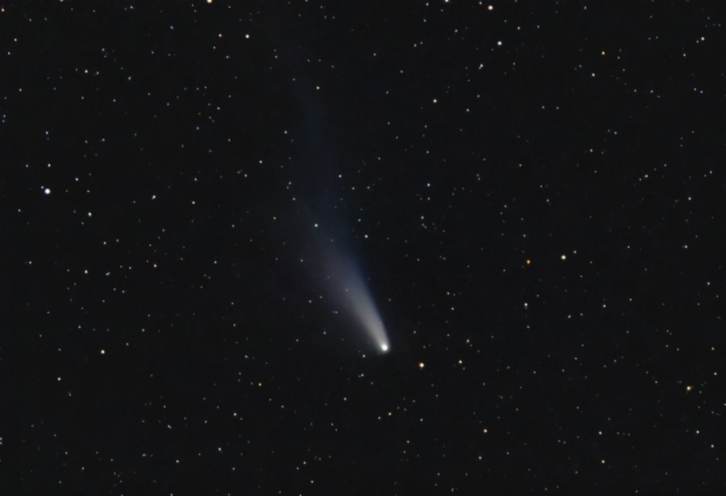 A white comet streaks through a starry night sky.