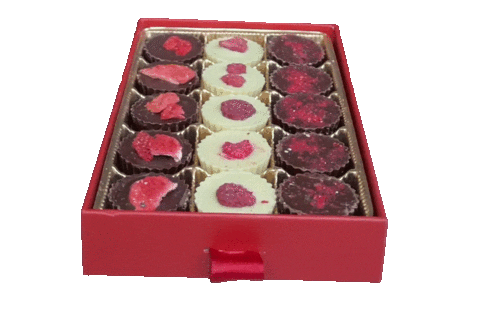 A rotating image of valentine's day chocolates. Dark, Milks, and white chocolate sit in rows inside a red box.