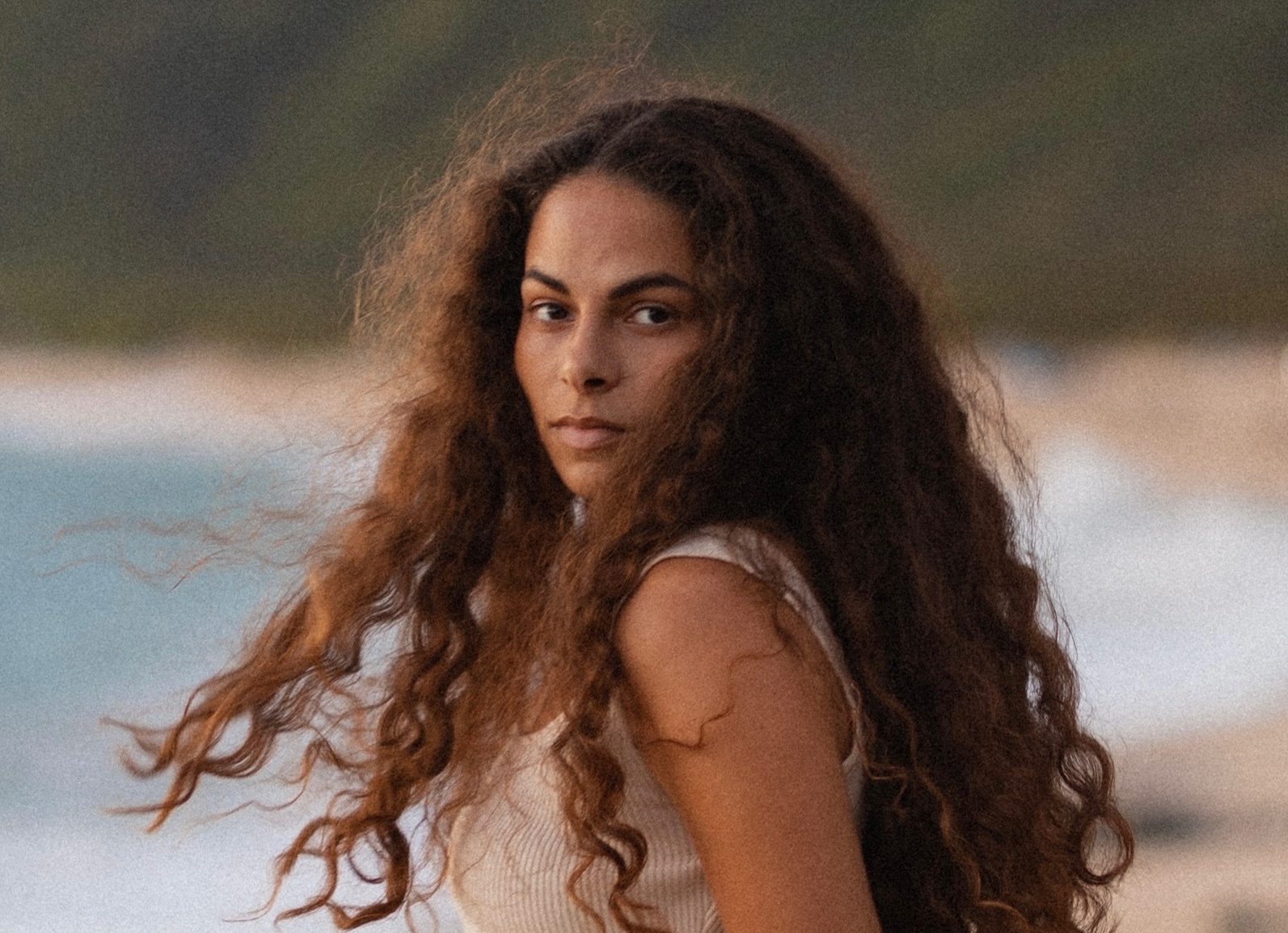 A photo of Sage Lenier in Keawa‘ula with a blurred background of a sandy beach