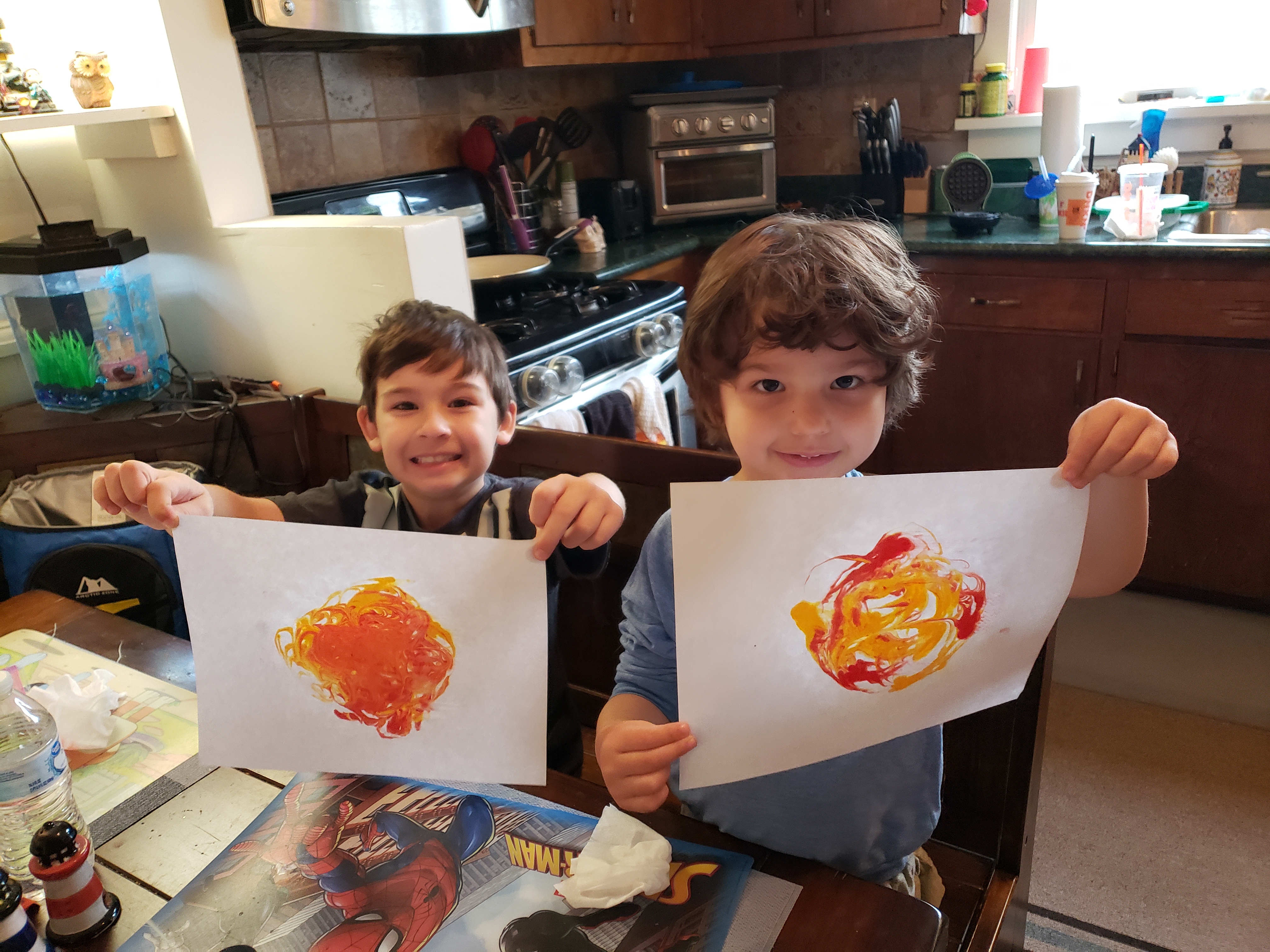 Two participants in their kitchen sharing sun pictures they drew
