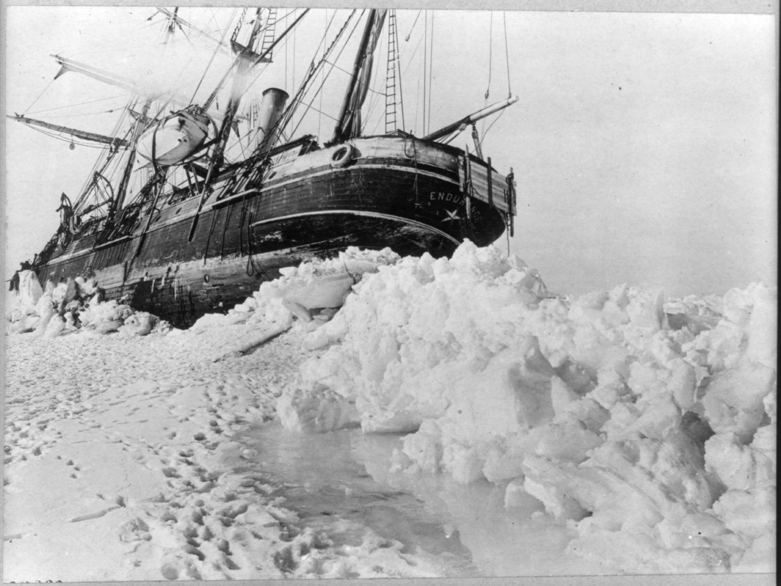 a black and white photograph of a large wooden ship stuck in antarctic ice