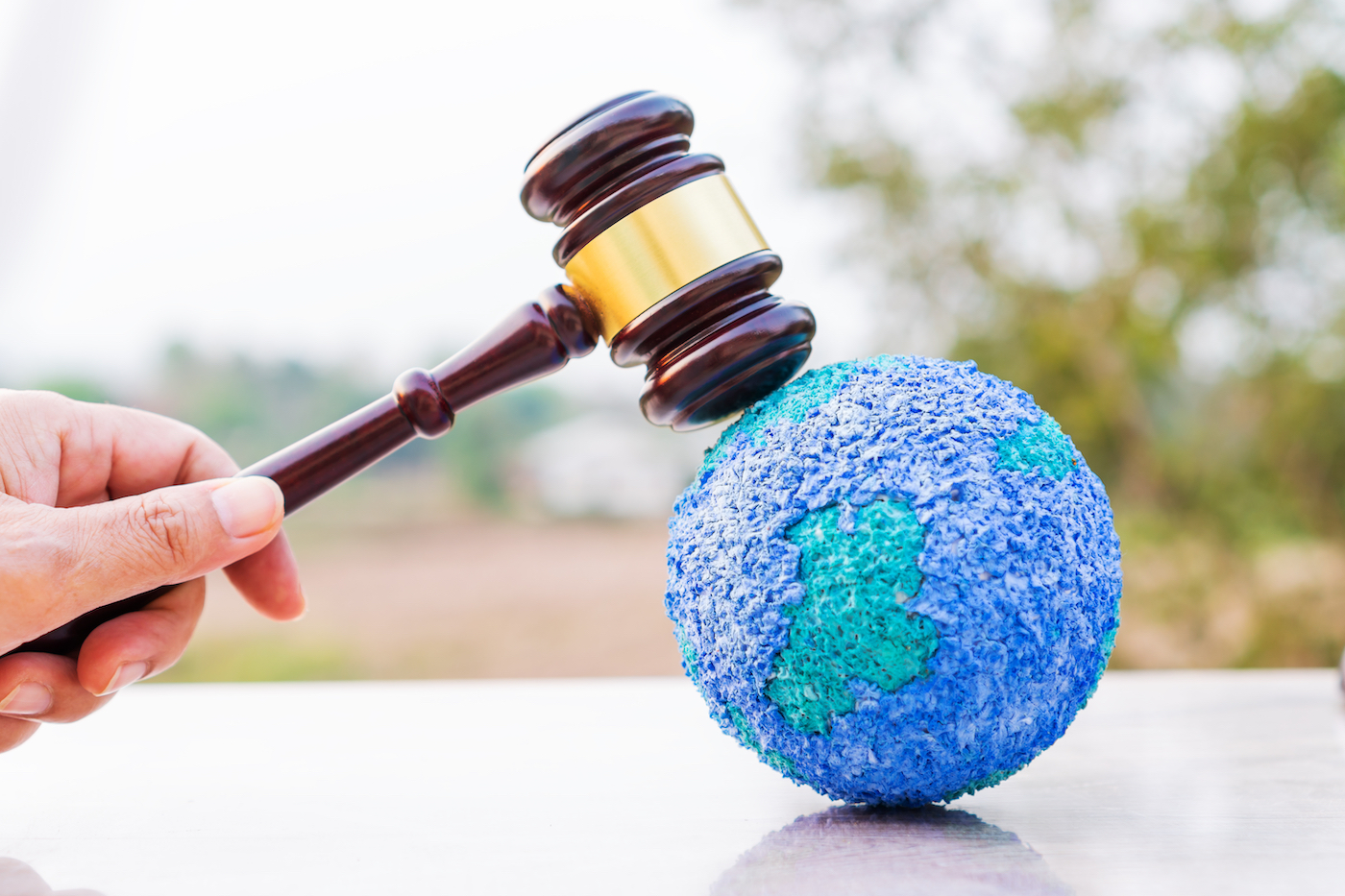 A gavel on top of a model of Earth made out of recycled plastic and chemicals