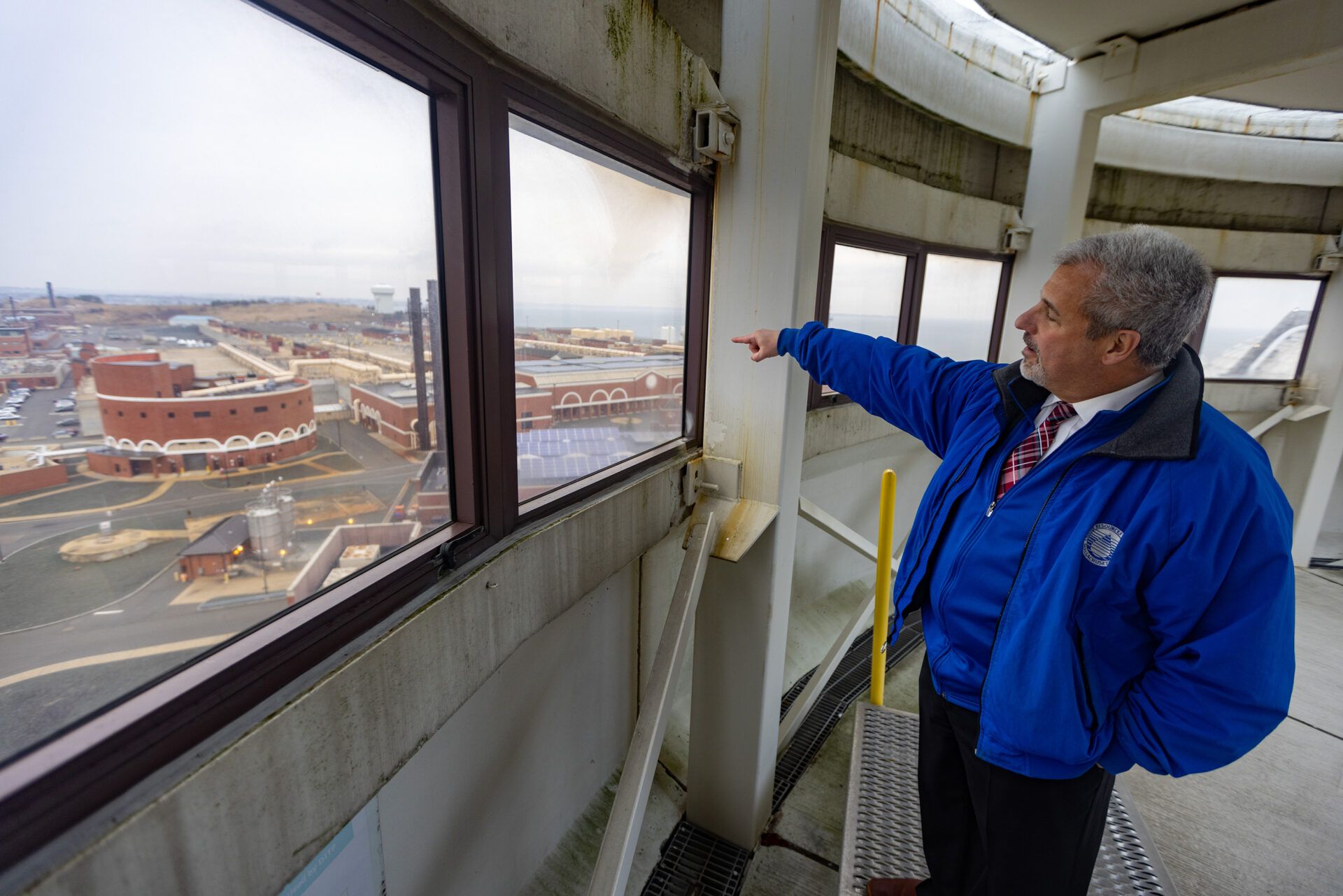 A man points out a window towards a water treatment facility