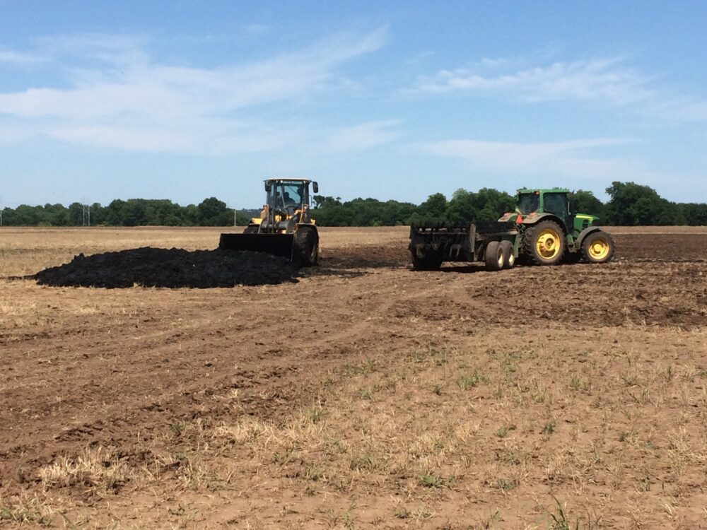 Tractors on an empty farm field with sewage sludge inside