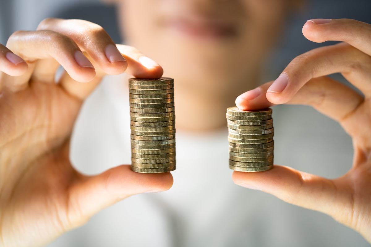 A woman hold two stacks of coins, one larger than the other.