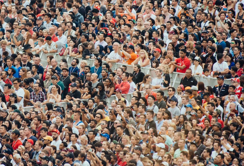 A multicultural crowd cheering in the stadium at a football game.