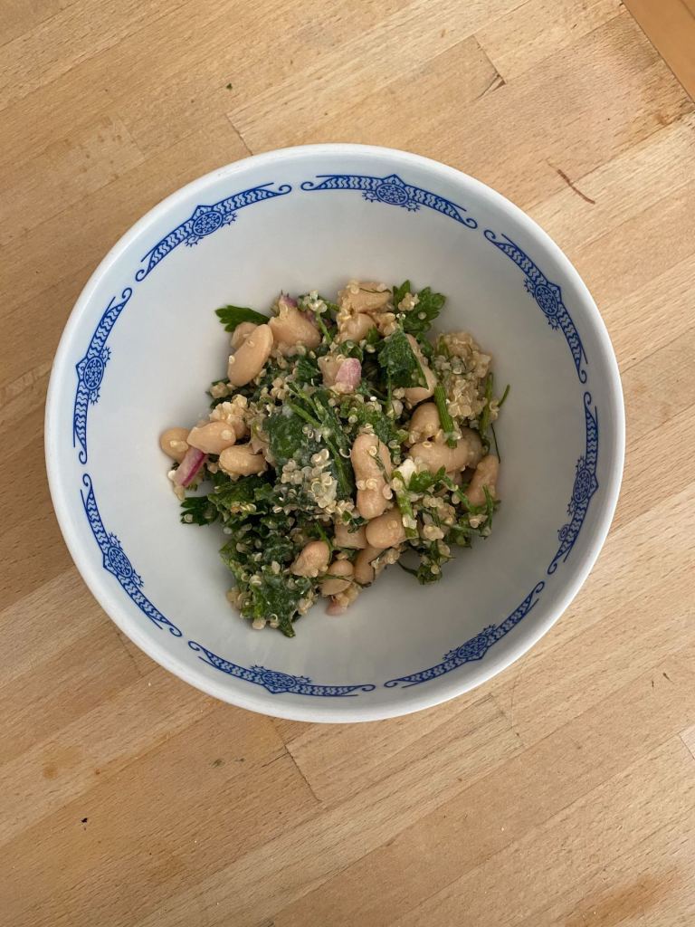 A ceramic bowl filled with white beans and greens. 