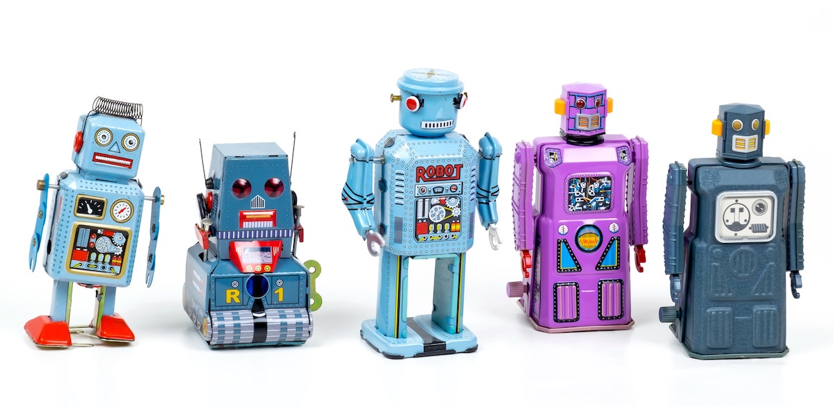 Five retro metal robot toys standing in a row.