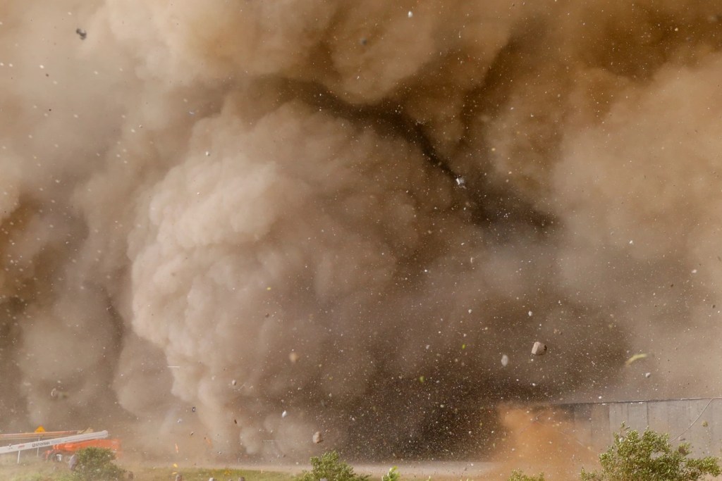 A cloud of brown debris with tiny particles blown around within it.