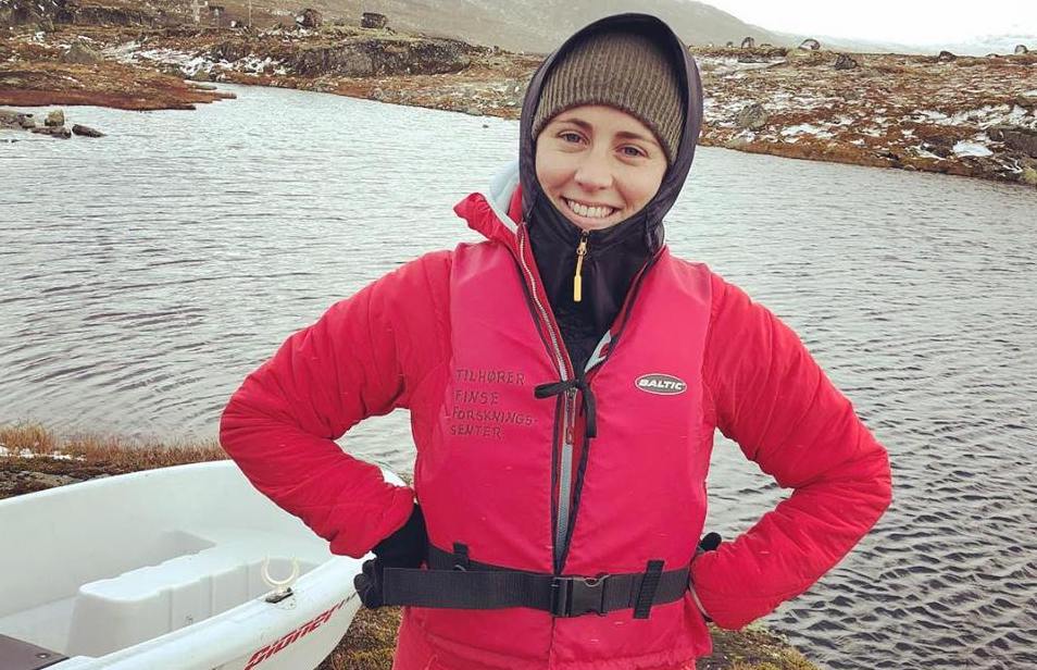 Rachel Lupien wearing a bright pink coat standing in front of a foggy lake.