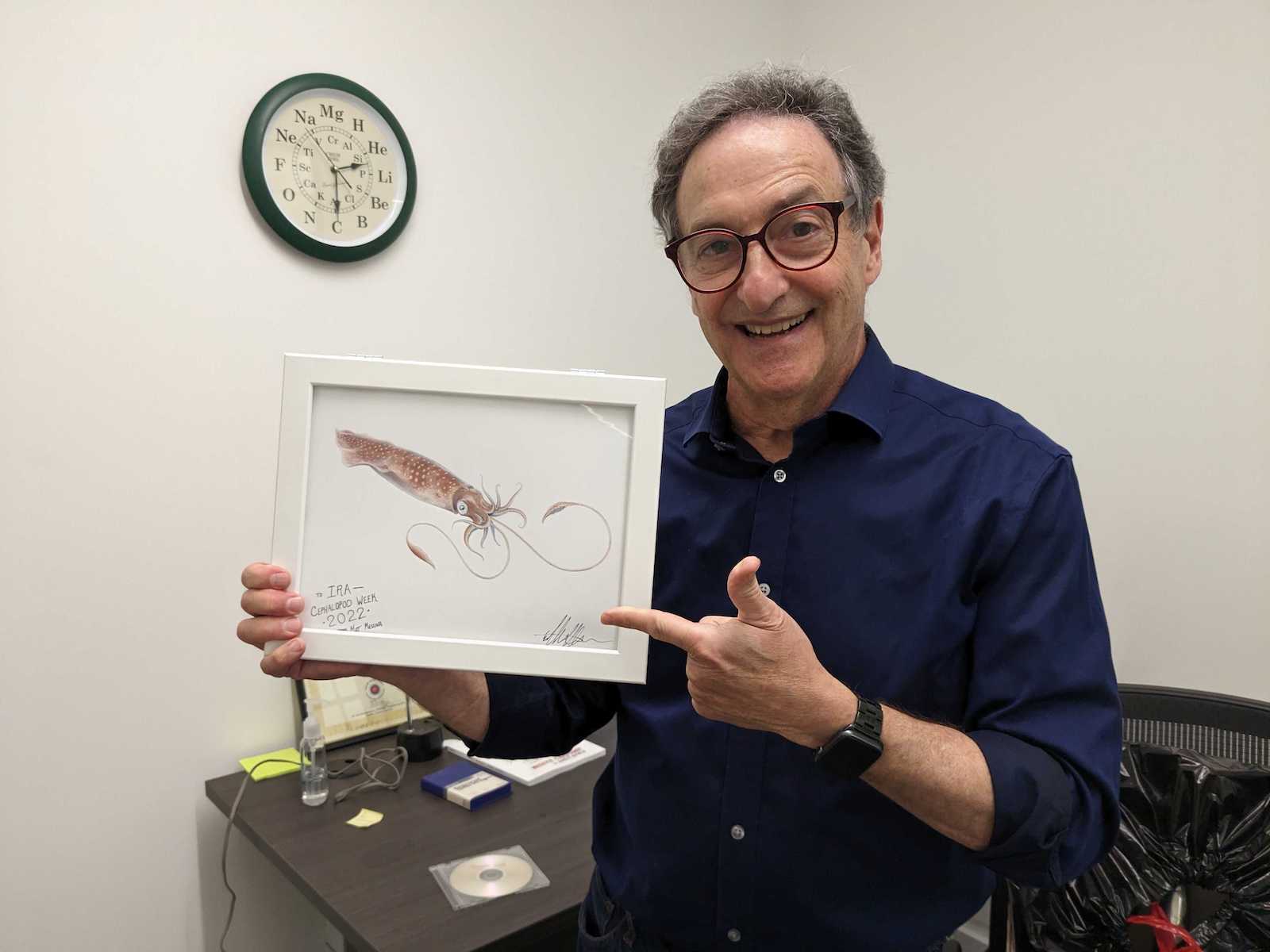 Ira Flatow holding up a colored pencil drawing of a squid.