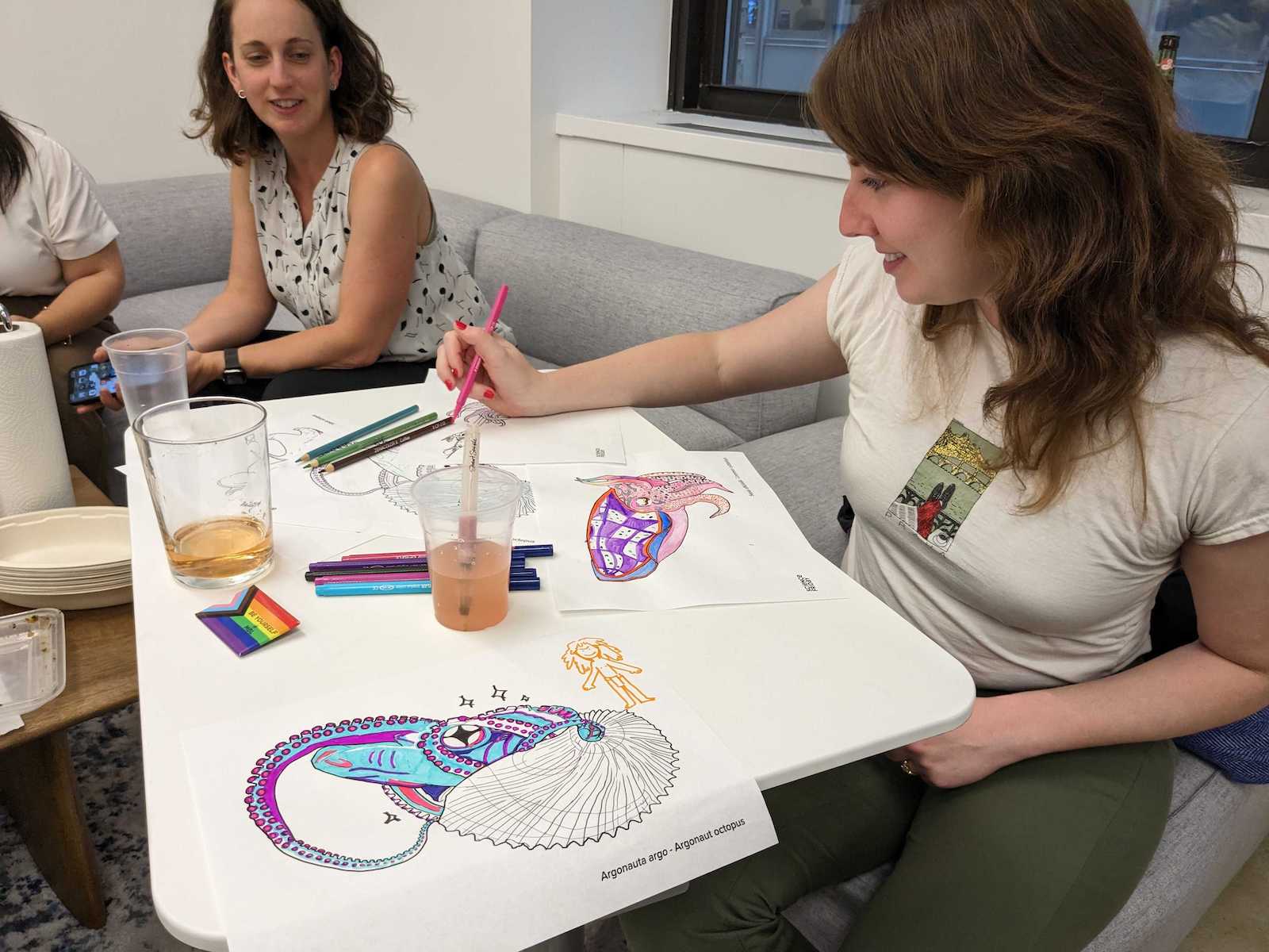 A woman holding a colored pencil and drawing on a blank coloring sheet. 