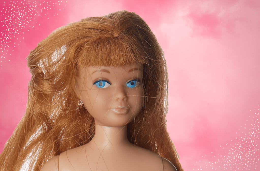 An old barbie doll face with a pink cloudy background