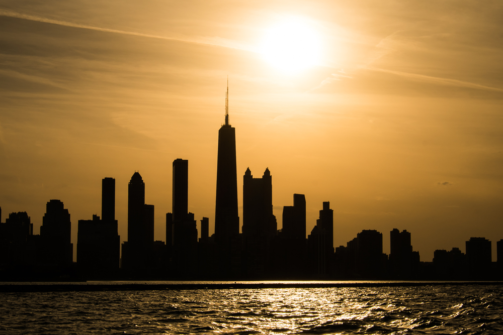 the sun sets behind chicago shadowing its skyline