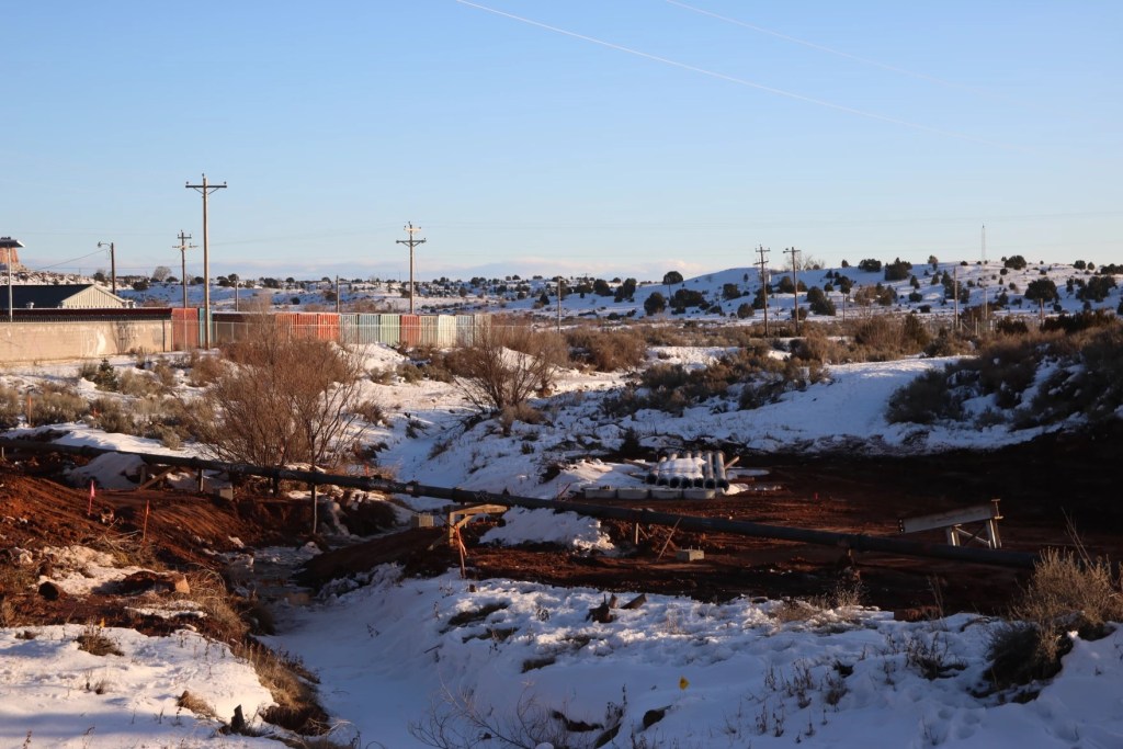 A snowy landscape with a large pipe across the ground.