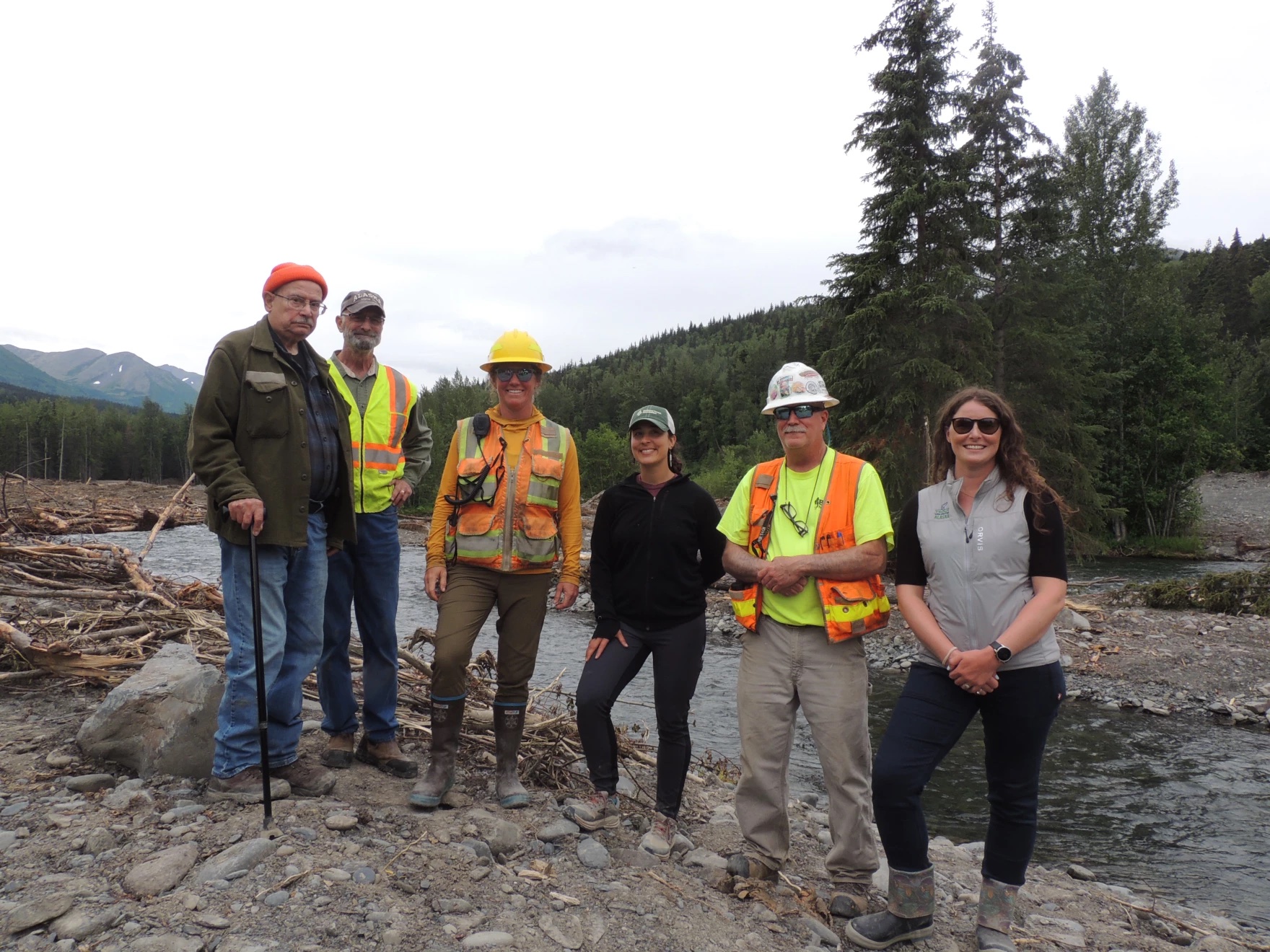 A group of people wearing hard hats and high visibility gear standing outside.