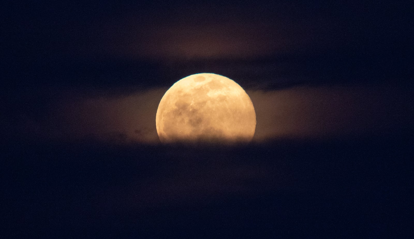 a full moon partially covered by clouds