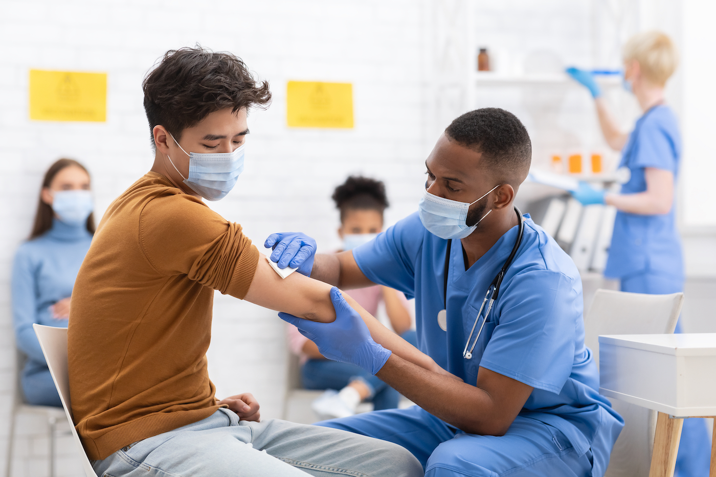 A doctor sanitizing a man's arm before vaccination